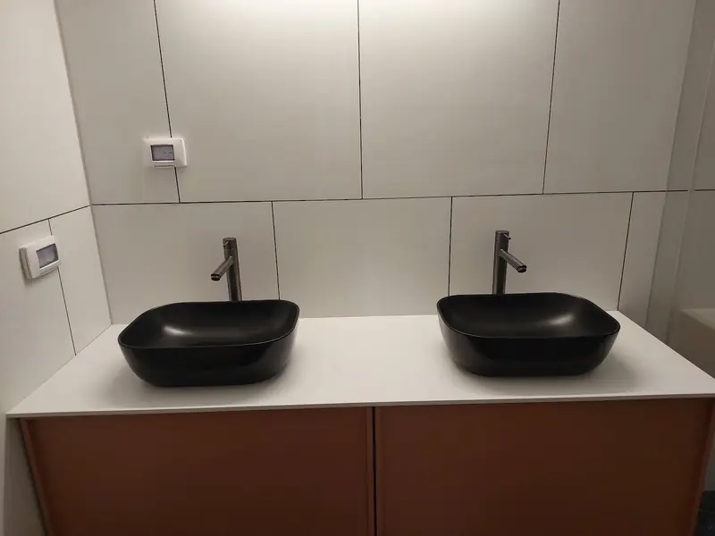 ארון אמבטיה עם משטח לבן ושני כיורים שחורים מונחים, ברזים גבוהים שחורים